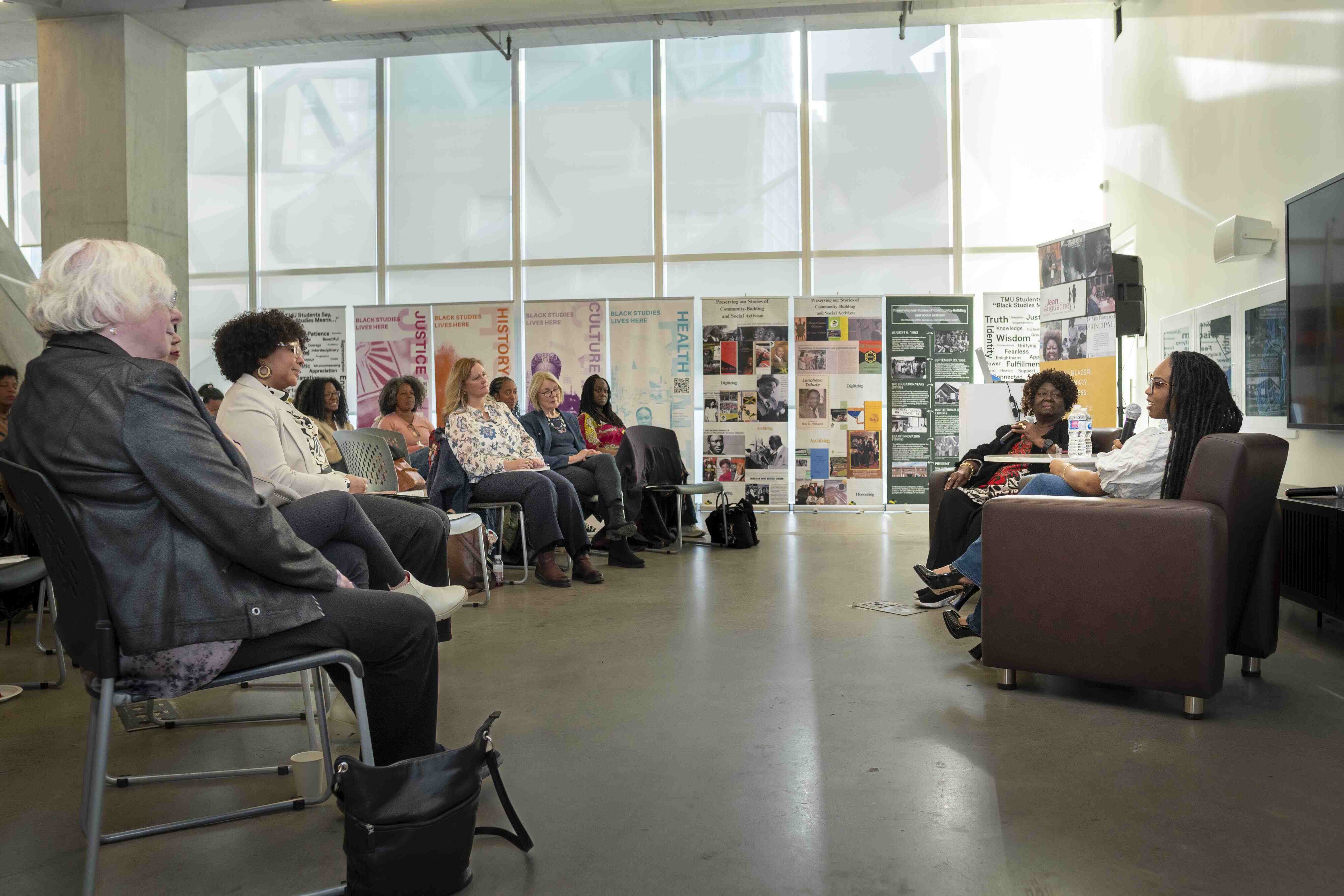 Event host Chelsi Campbell in conversation with Jean Augustine. In the audience there is a diverse group of students, faculty, and community members.